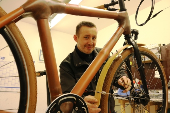 Ein Mitarbeitender baut ein Fahrrad aus Bambus zusammen.  