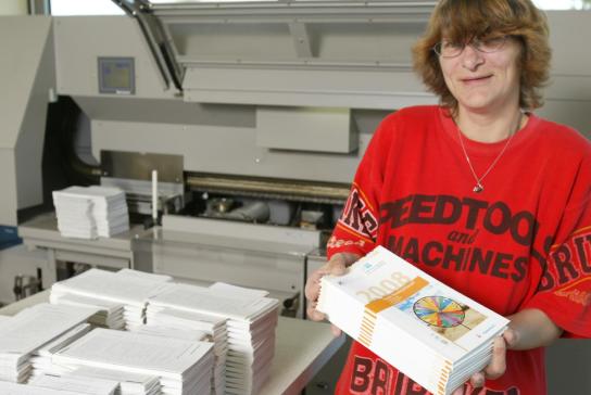 Eine Mitarbeiterin zeigt die fertigen Druckerzeugn