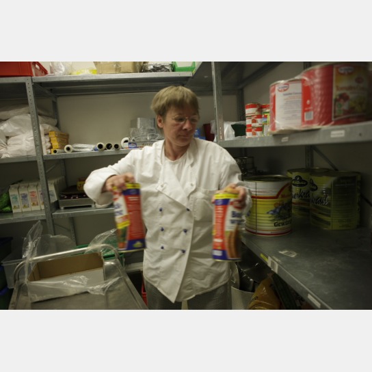 eine Küchenmitarbeiterin packt Konservendosen in 